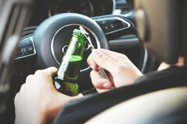 A man holding a beer bottle inside a car